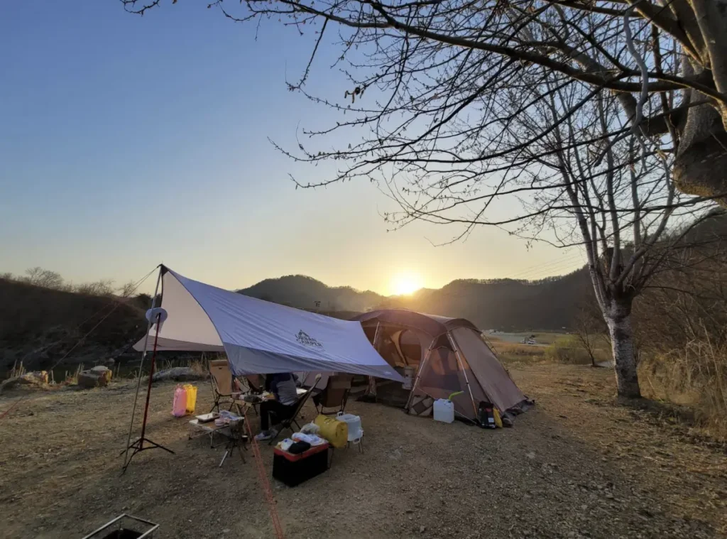 타프와 텐트 옆으로 홍천강이 흐르고 산넘어로 아침해가 떠오르는 모습