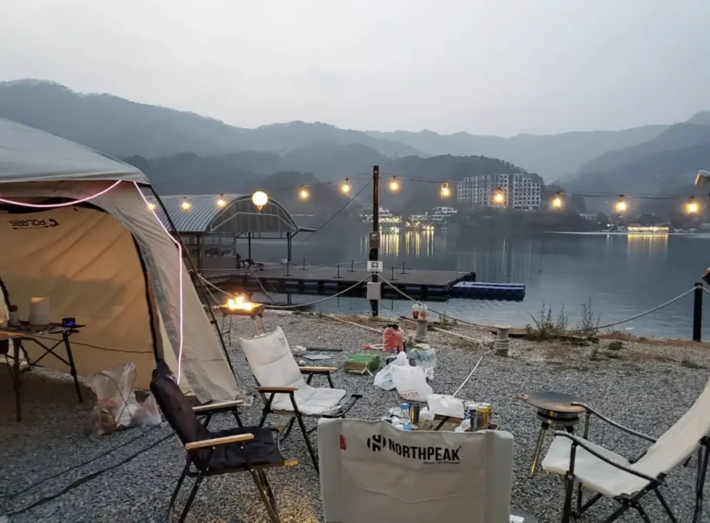 텐트옆 테이블과 의자가 놓여져있고 북한강이 보이는 모습